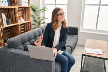 Klinikte dizüstü bilgisayar kullanan genç bir kadın.