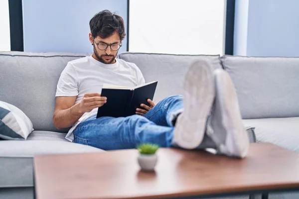 Jovem Hispânico Homem Ler Livro Sentado Sofá Casa — Fotografia de Stock