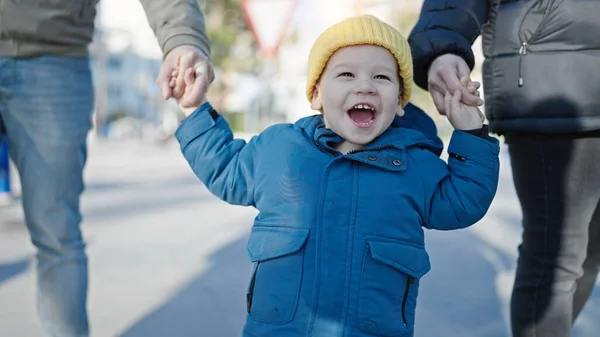 stock image Caucasian toddler smiling cheerful holding hands with mum and dad at street