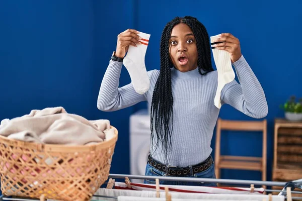 Mujer Afroamericana Sosteniendo Calcetines Cara Choque Mirando Escéptico Sarcástico Sorprendido —  Fotos de Stock