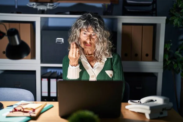 コンピュータのラップトップを使用して夜に働く中世の女性手と指でイタリアのジェスチャーを行う自信を持って表現 — ストック写真