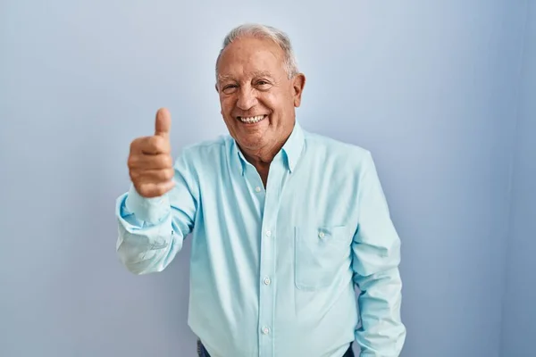 Senior Man Met Grijs Haar Staan Blauwe Achtergrond Tonen Wijzen — Stockfoto