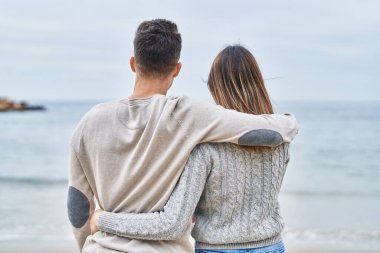 Man and woman couple hugging each other on back view at seaside