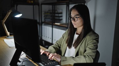 Ofiste çalışan genç ve güzel İspanyol bir iş kadını bilgisayar kullanıyor.