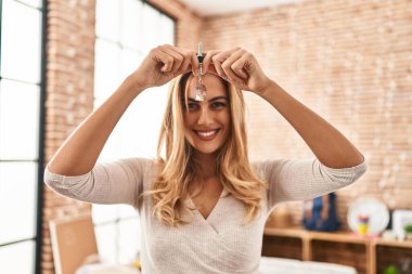 Young blonde woman smiling confident holding key of house at new home