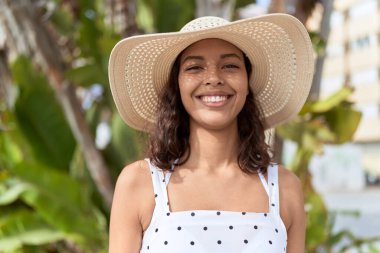 Genç Afrikalı Amerikalı kadın parkta kendine güvenen yaz şapkası takıyor.