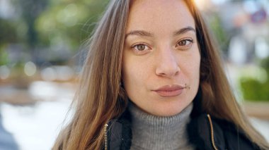 Young caucasian woman standing with serious expression at park