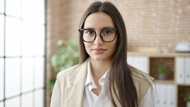 Young beautiful hispanic woman business worker standing with relaxed expression at office