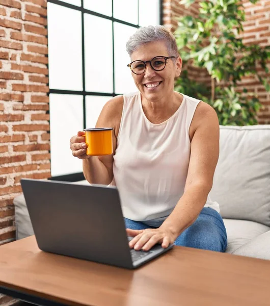 Μέση Ηλικία Γυναίκα Πίνοντας Καφέ Χρησιμοποιώντας Φορητό Υπολογιστή Στο Σπίτι — Φωτογραφία Αρχείου