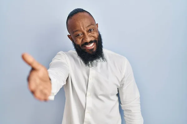 Afroamerikansk Man Står Över Blå Bakgrund Leende Vänlig Erbjuder Handslag — Stockfoto