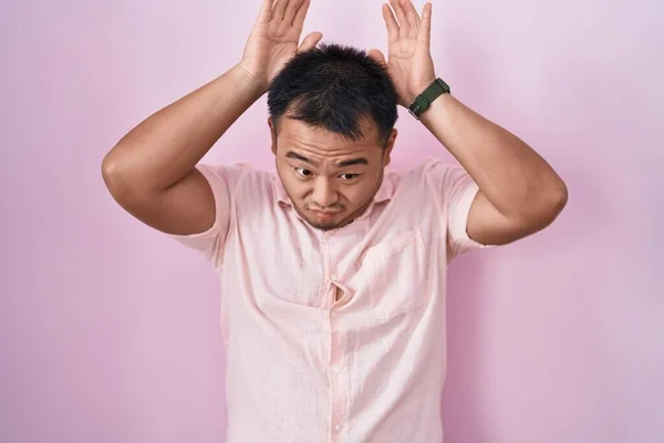 Китайский Молодой Человек Стоящий Розовом Фоне Делающий Жест Кроличьих Ушей — стоковое фото