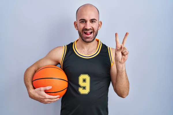 年轻的秃头男子 留着胡子 身穿篮球服 笑容满面 微笑着看着镜头 用手指做胜利的标志 第二点 — 图库照片