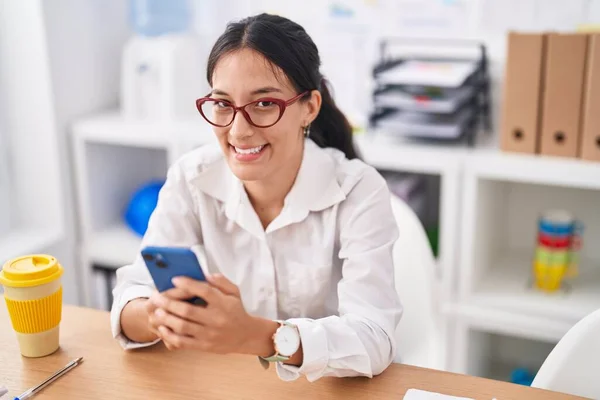 オフィスで働くスマートフォンを使っている若い美しいヒスパニック系女性のビジネスワーカー — ストック写真