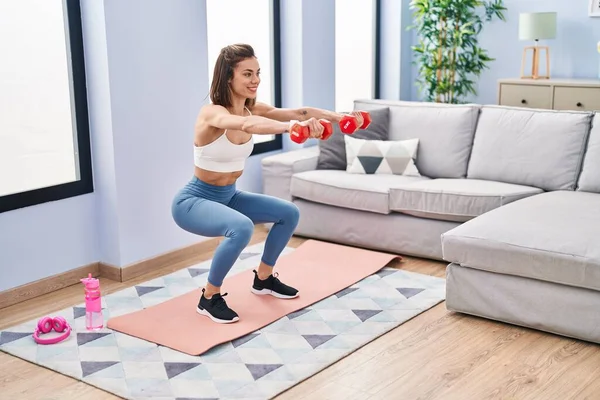 Young Beautiful Hispanic Woman Training Leg Exercise Using Dumbbells Home — Stockfoto