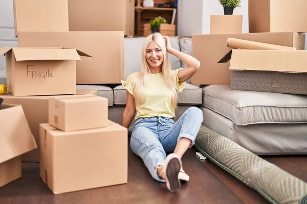 stock image Young blonde woman smiling confident relaxed sitting on floor at new home