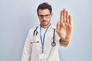 Doktor üniforması giyen ve steteskop kullanan genç İspanyol bir adam avucunun içi gibi şarkı söylemeyi kesiyor. Yüzünde olumsuz ve ciddi bir jest olan uyarı ifadesi. 