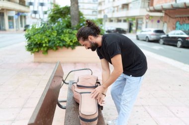 Genç İspanyol müzisyen. Parkta gitar çantası açıyor.