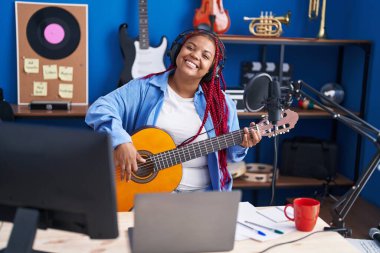 Afrikalı Amerikalı kadın müzisyen müzik stüdyosunda klasik gitar çalıyor.