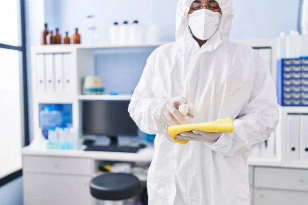 实验室里 身穿医用口罩 头戴医用口罩的年轻科学家在布上倒入清洁剂凝胶 — 图库照片