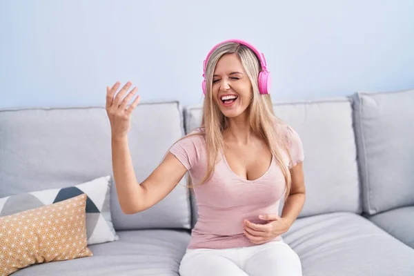 Young Blonde Woman Listening Music Doing Guitar Gesture Home — Stock Photo, Image