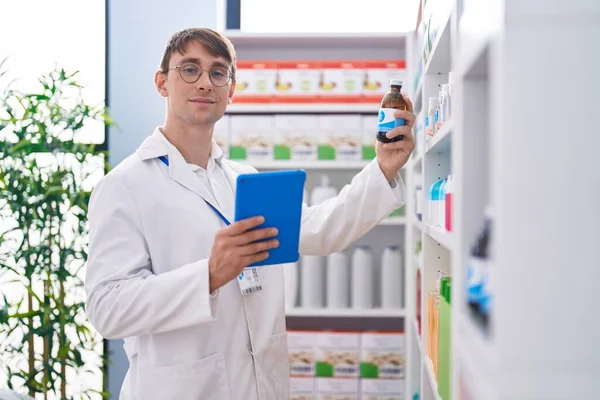 Young Caucasian Man Pharmacist Using Touchpad Holding Medicine Bottle Shelving — Foto Stock