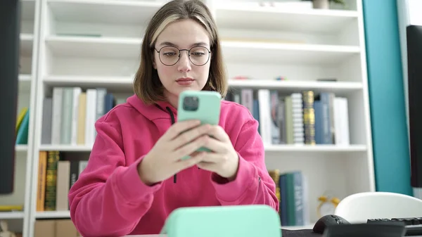 図書館大学でスマホを使う若いブロンド女子学生 — ストック写真