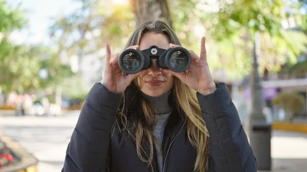 年轻的高加索女人在公园用双筒望远镜充满自信地微笑 — 图库照片