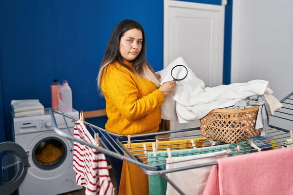 Young Hispanic Woman Holding Magnifying Glass Looking Stain Clothes Relaxed — Stock Photo, Image