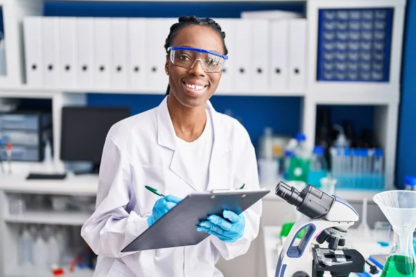 Afrikanische Wissenschaftlerin Lächelt Selbstbewusst Und Schreibt Labor Auf Dokument — Stockfoto