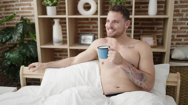 Stock image Young caucasian man drinking a coffee sitting on bed shirtless at bedroom