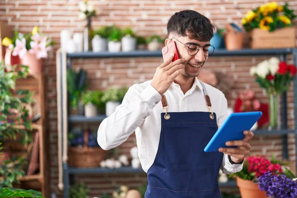 stock image Young hispanic man florist talking on smartphone using touchpad at florist