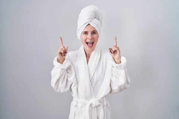 Blonde Caucasian Woman Wearing Bathrobe Smiling Amazed Surprised Pointing Fingers — Stock Photo, Image
