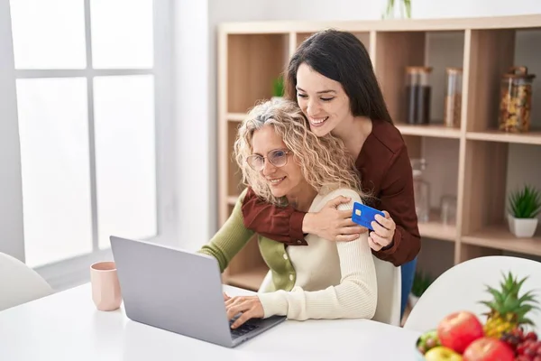 Stock image Two women mother and daughter using laptop and credit card at home