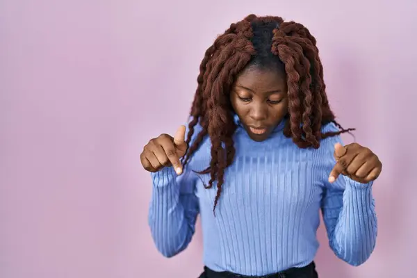 Африканская Женщина Стоит Розовом Фоне Указывая Вниз Пальцами Показывая Рекламу — стоковое фото