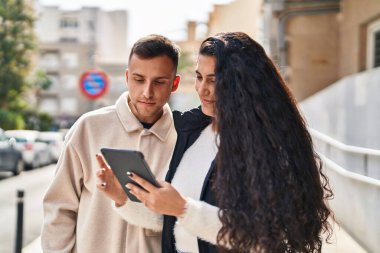 Man and woman smiling confident using touchpad at street