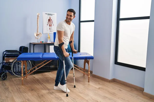 Young Hispanic Man Injured Physiotherapy Patient Using Crutches Walking Rehab — Fotografia de Stock