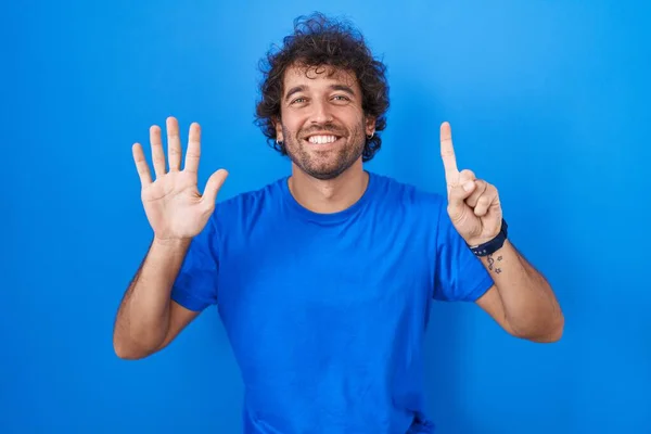 Spanischer Junger Mann Steht Vor Blauem Hintergrund Und Zeigt Mit — Stockfoto