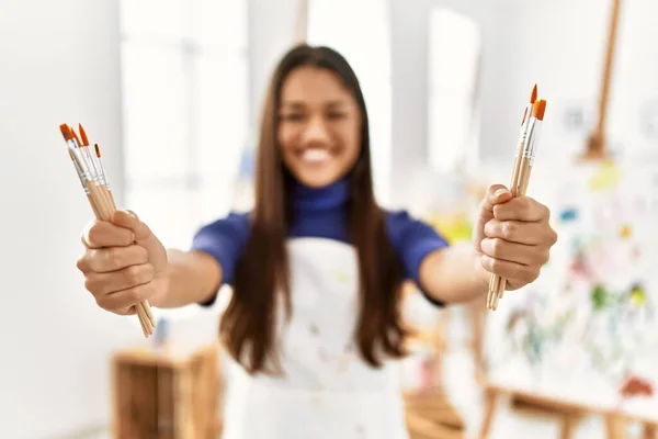 年轻的拉丁女人笑着自信地拿着画笔在艺术工作室里 — 图库照片
