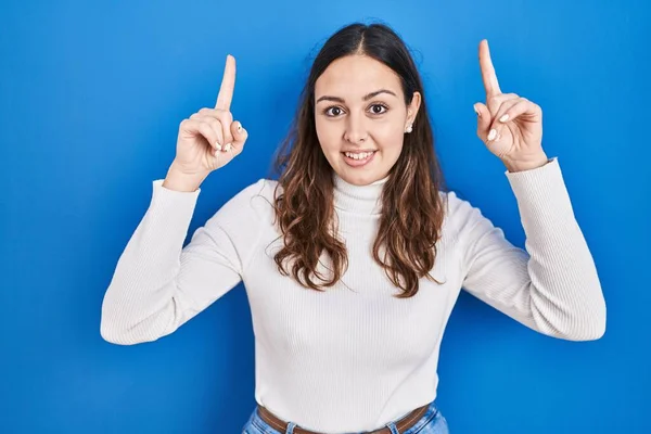 Young Hispanic Woman Standing Blue Background Smiling Amazed Surprised Pointing — Stock Photo, Image
