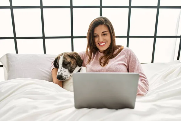 Молодая Женщина Помощью Ноутбука Обнимает Собаку Сидя Кровати Спальне — стоковое фото