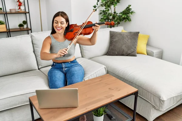 年轻美丽的他的惊慌失措的女人在家里的沙发上坐着在线小提琴课 — 图库照片
