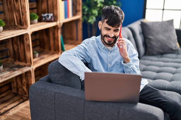Genç Spanyol Adam Dizüstü Bilgisayar Kullanıyor Evde Akıllı Telefonla Konuşuyor — Stok fotoğraf