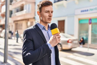 Sokakta mikrofon kullanan genç bir muhabir.
