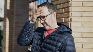 Çağrı merkezi kulaklığı takan orta yaşlı bir adam mutlu bir gülümseme ve el kaldırarak zaferi kutluyor. 