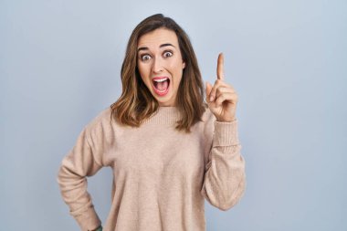 İzole edilmiş arka planda duran genç bir kadın başarılı bir fikri işaret ediyor. Heyecanlı ve mutlu. Bir numara.. 