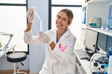 Laboratuvarda test tüpüne sıvı döken genç İspanyol bilim kadını.