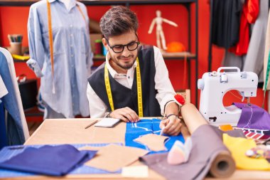 Genç İspanyol terzi gülümsüyor atölyedeki kumaşta iz bırakıyor.