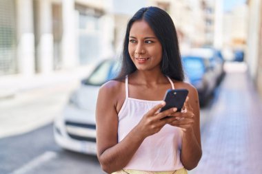 Sokakta akıllı telefon kullanan kendine güvenen güzel bir kadın.