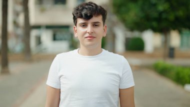 İkili olmayan adam parkta ciddi bir ifadeyle duruyor.