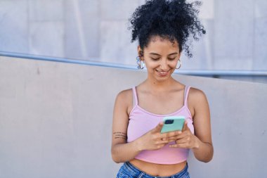 Sokakta akıllı telefon kullanan, kendine güvenen genç İspanyol kadın.